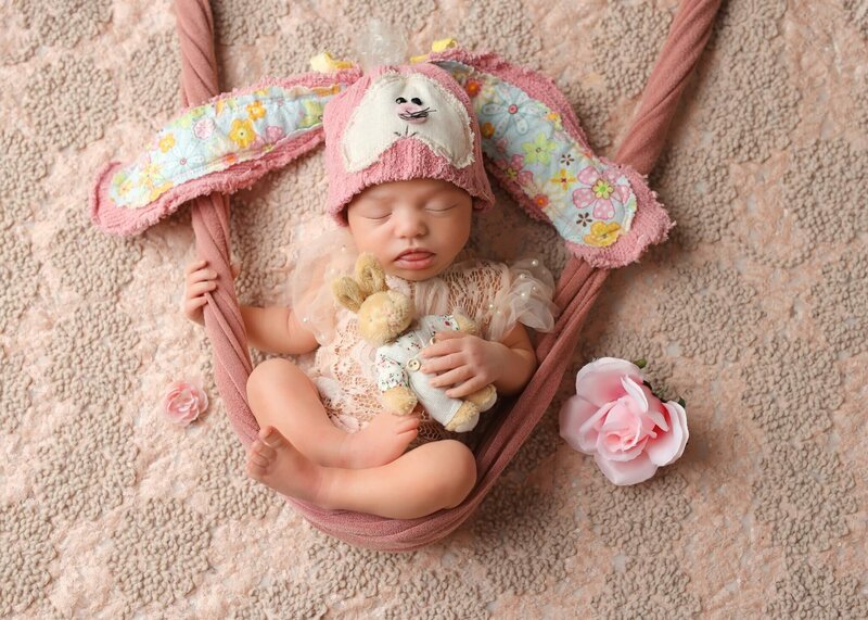 sleeping baby posing in flowy bunny hat in blush wrap swing