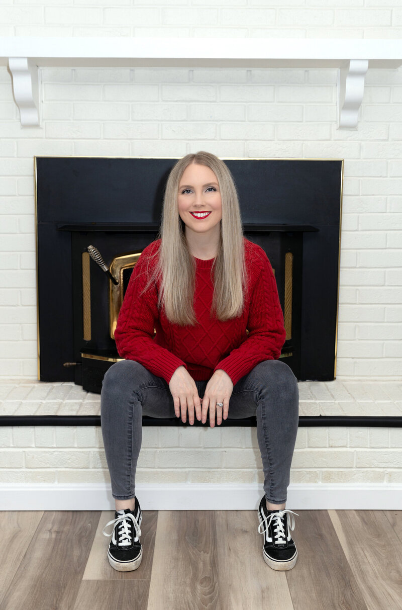 Kristyn sitting in front of her fireplace smiling
