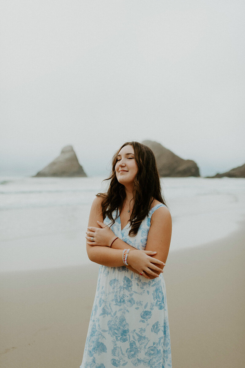 girl in blue floral dress standing on Oregon coast at Heceta Head Lighthouse Beach
