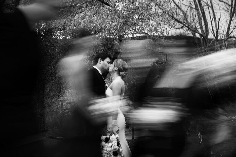 A bride and groom kissing in a blur of wedding guests