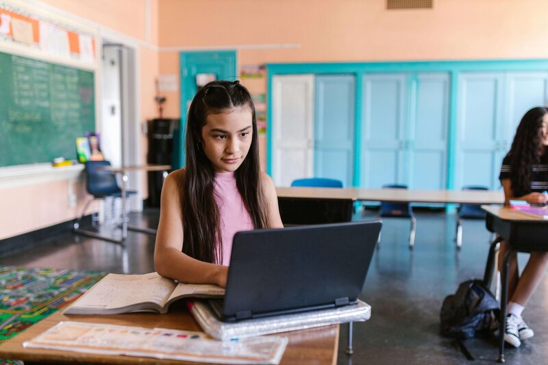 Student in class working on her laptop at her desk