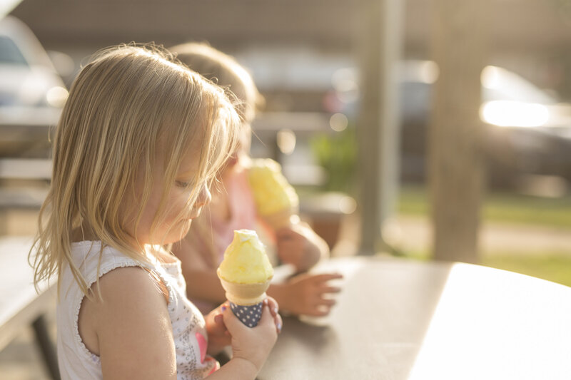 Little girl eating a yellow  ice cream cone
