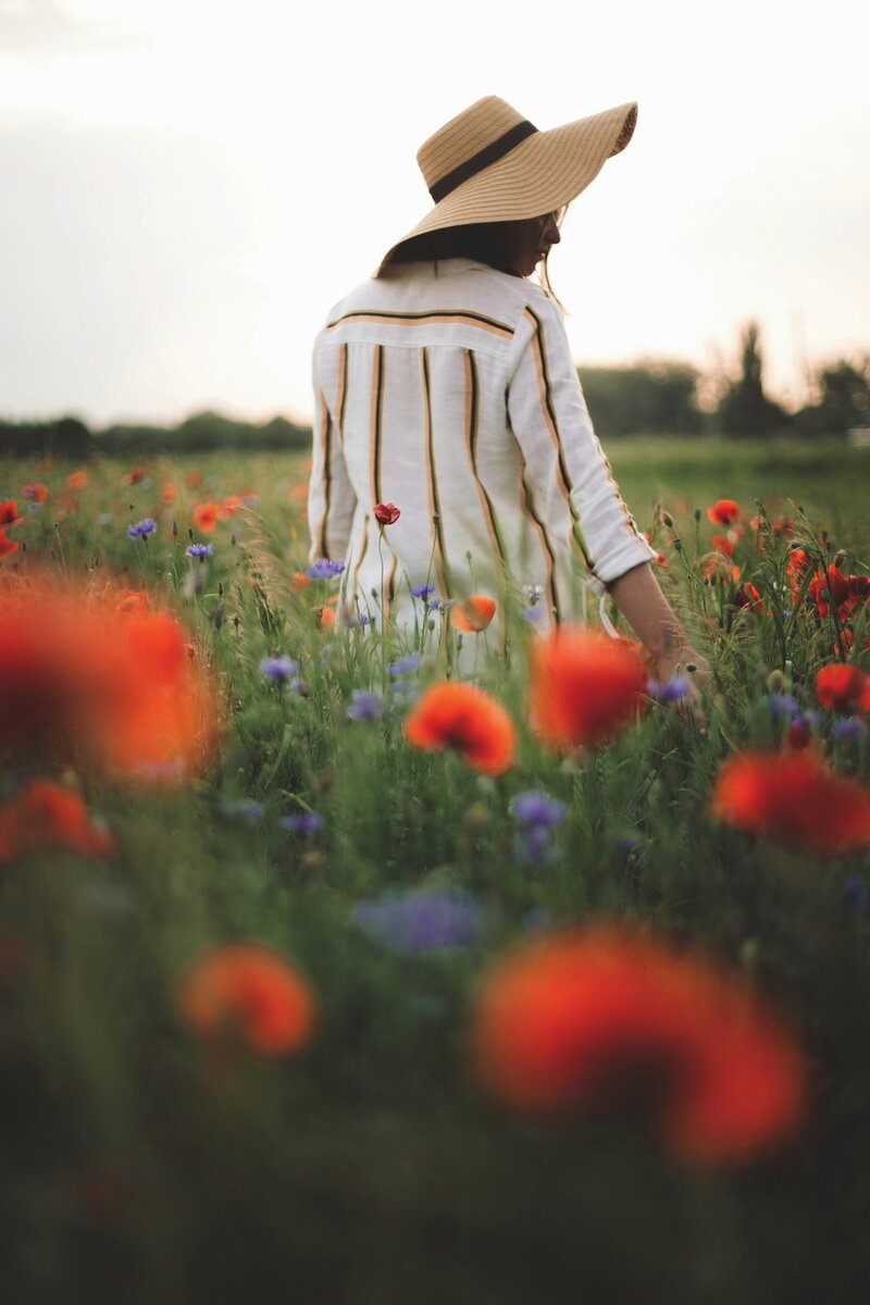Woman walking through a sunlit field of wildflowers at Chateau Charente, embracing a slow, mindful morning as part of the retreat’s wellness experience with tai chi, meditation, and nature walks,