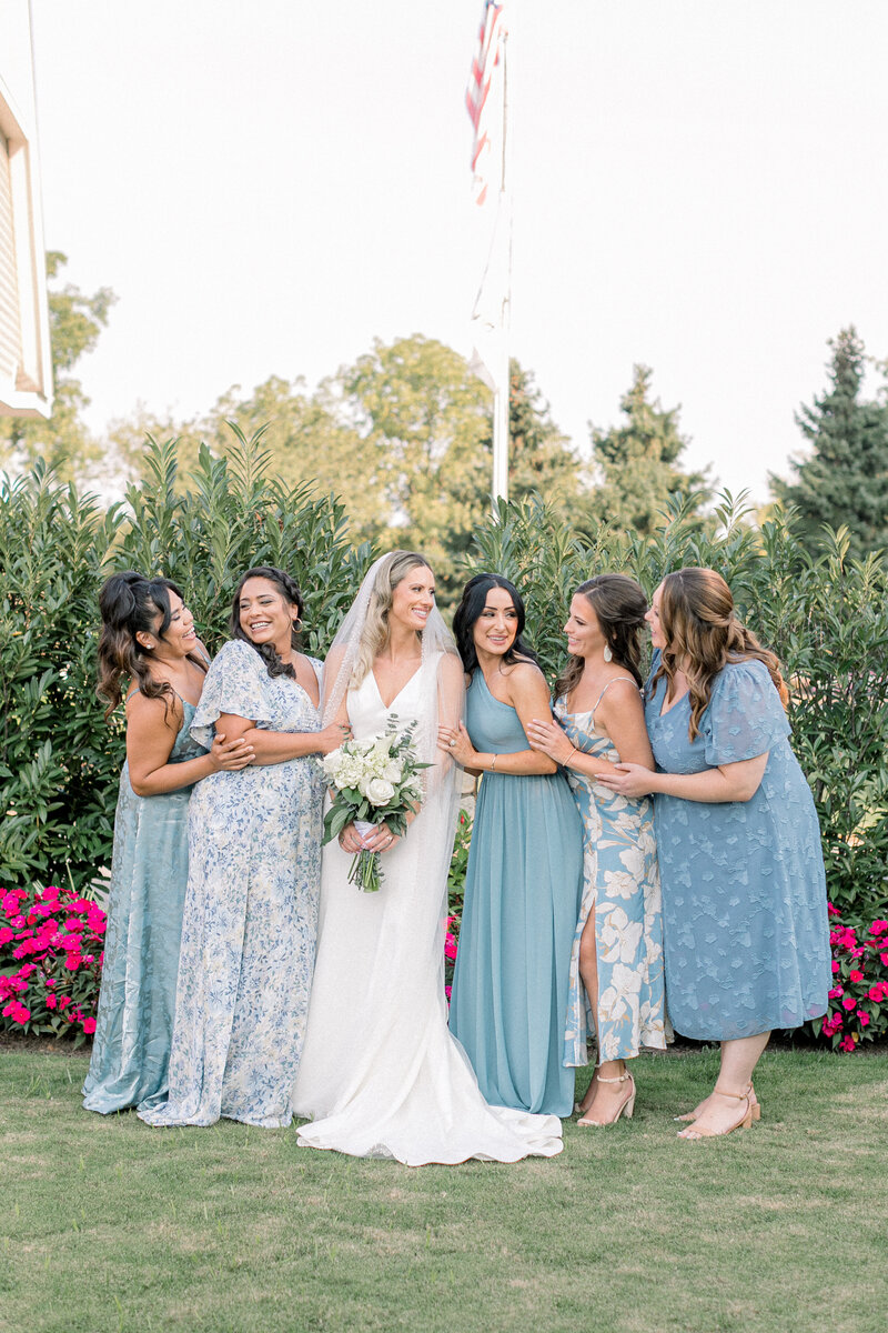 Bride with Bridesmaids laughing. Bridesmaids wearing light blue dresses with floral patterns.