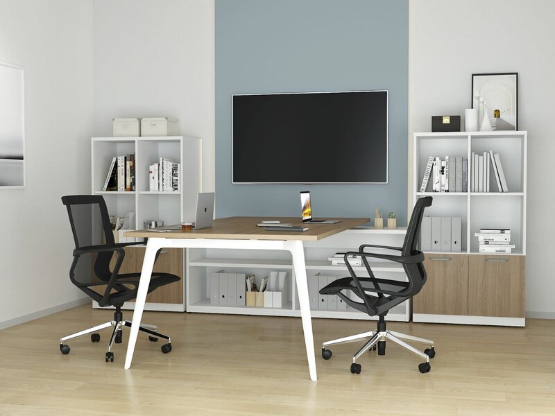 long desk with black mesh chairs and light wood floors