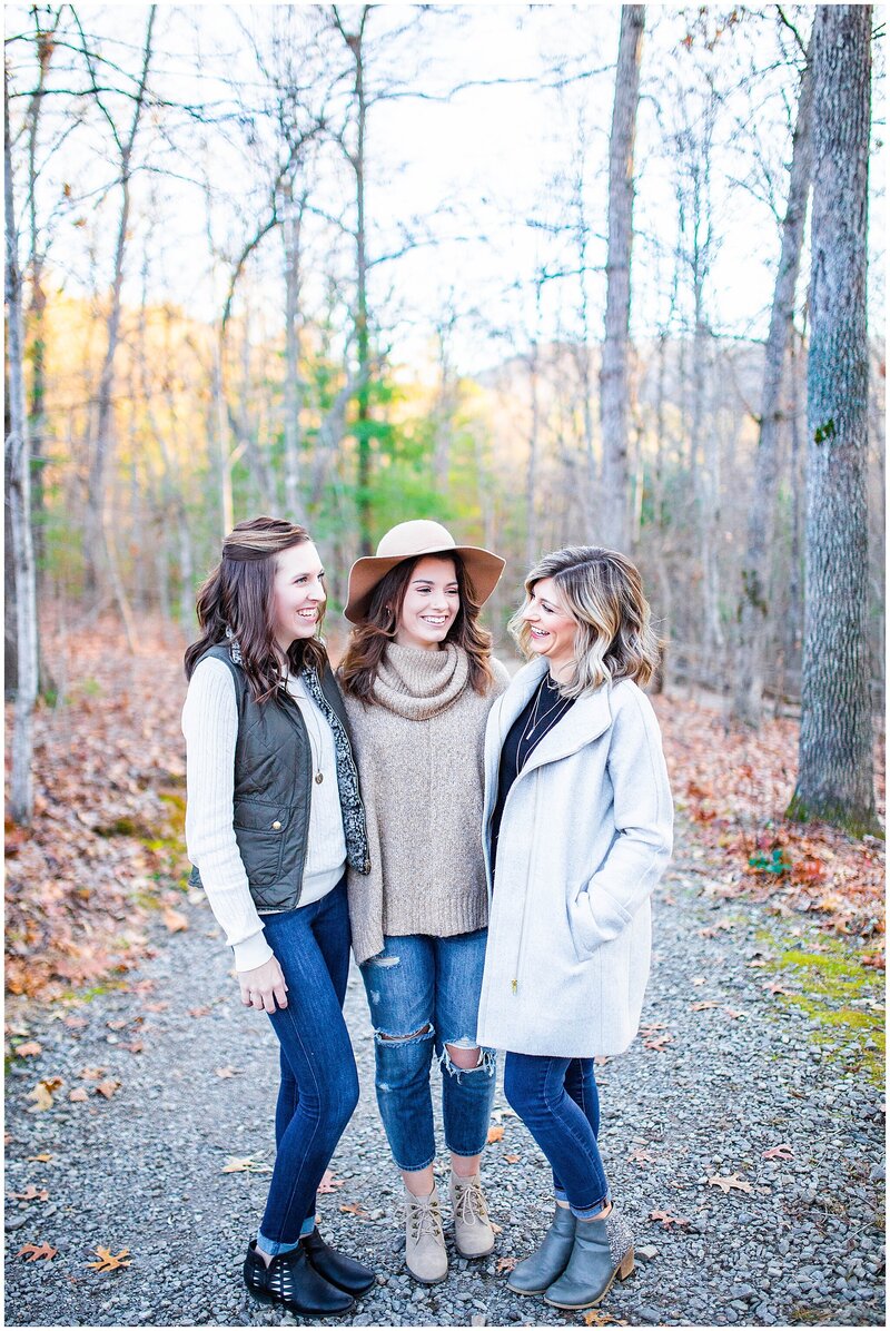 three sisters posing for fall photos with jackets and hat on