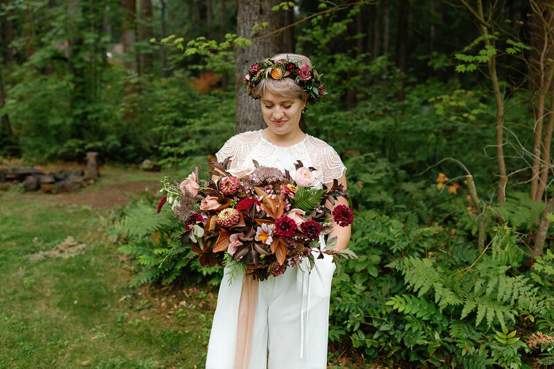 Woman wearing floral crown and looking down at wedding bouquet