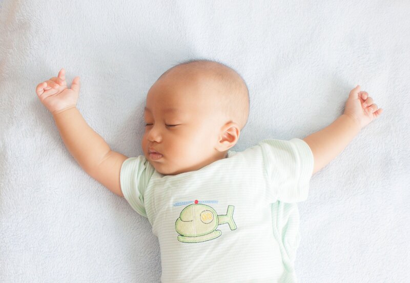 baby with their arms outstretched sleeping