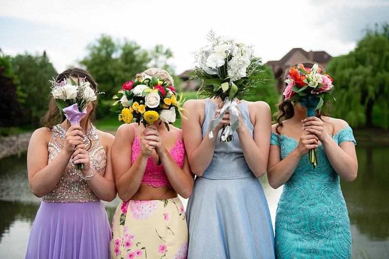 High school senior girls before Prom holding floral bouquets in front of their faces