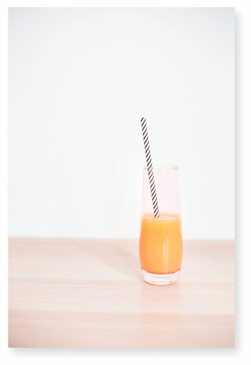 Mimosa drink in a pink stemless glass with a black and white paper straw