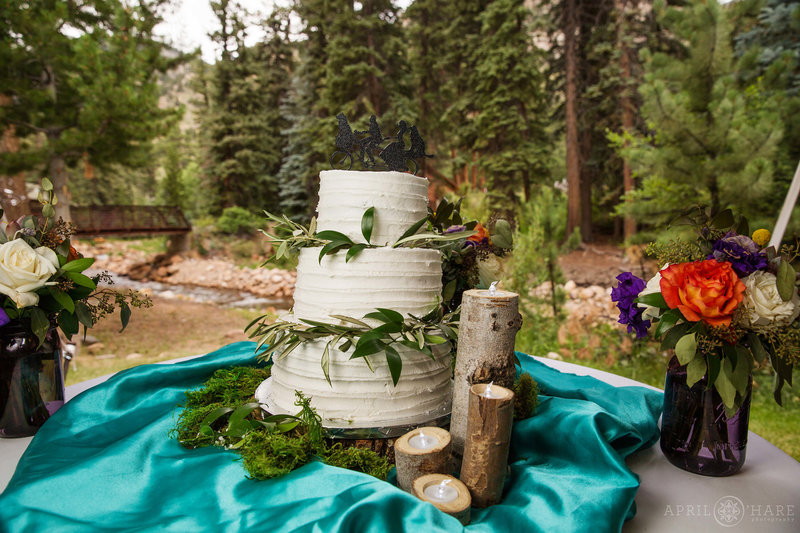 Cute white cake with greenery decorating it under the tent at the Estes Park Condos on Fall River