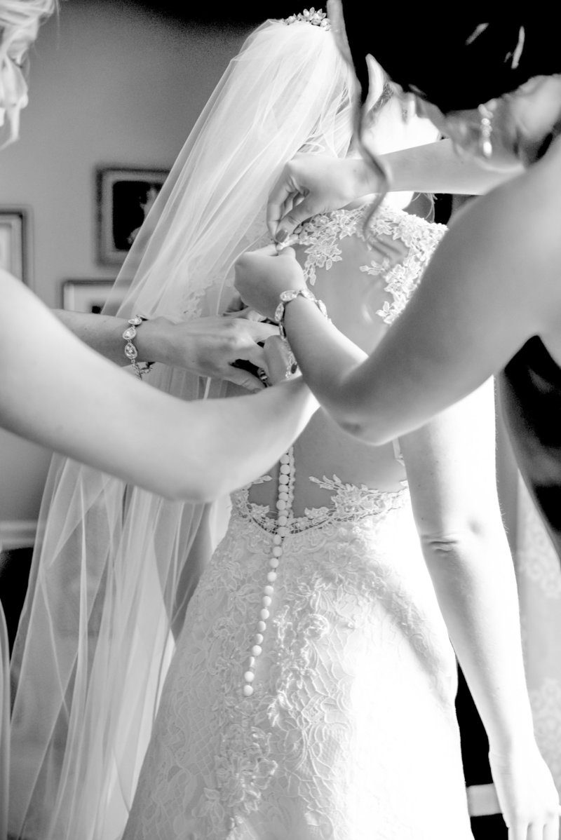 Bridesmaids zip up a brides dress