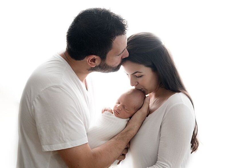 dad kissing mom, and mom kissing newborn boy