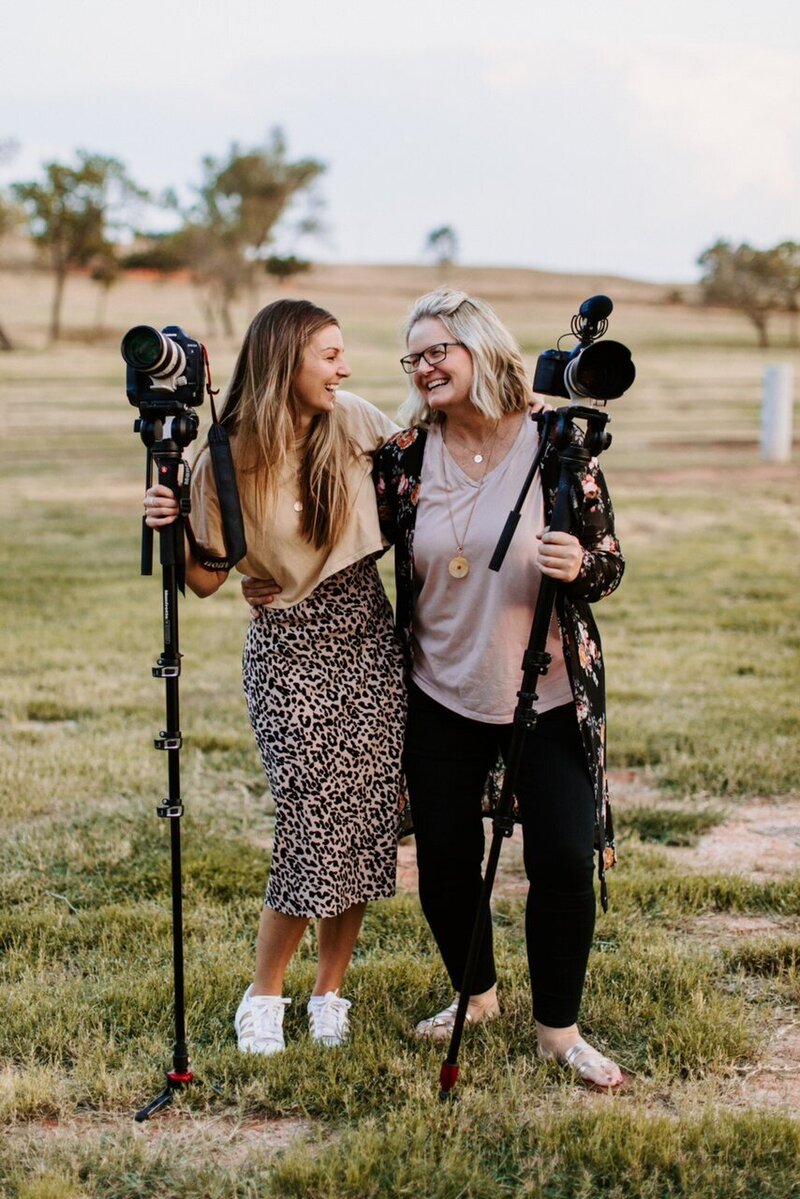 Kaylyn and Dana Pulley holding their cameras and smiling at each other