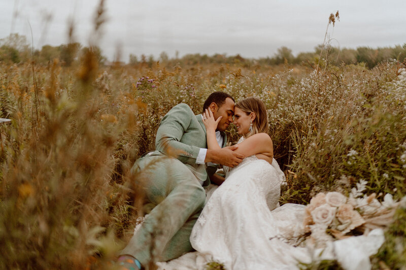 bride and groom laying in the grass field