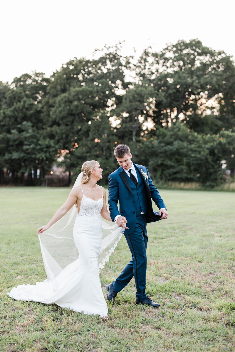 Bride and groom walk through a field at the emerson