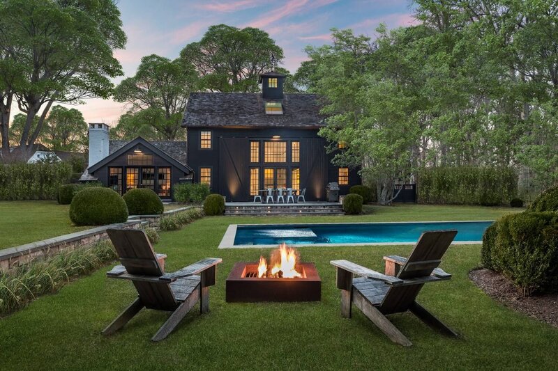 Black wood modern farmhouse venue rental featuring muskoka chairs and a pool