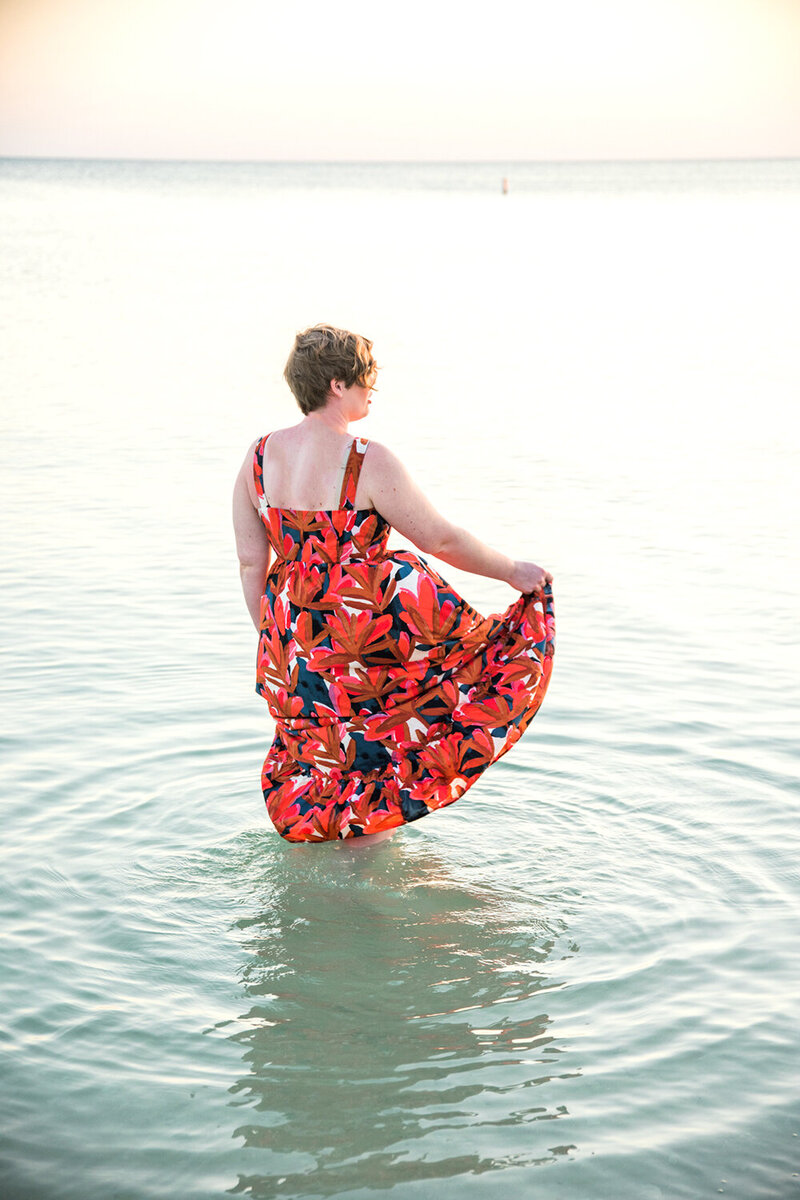 Woman walking in the ocean in a red dress