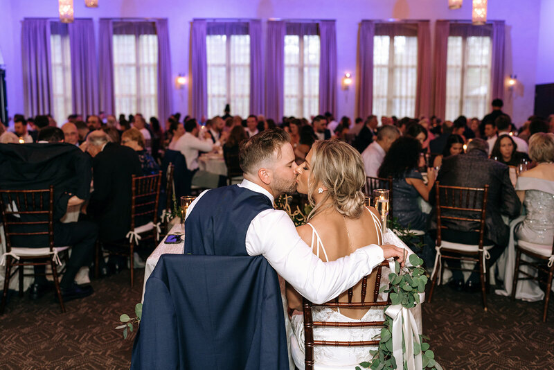bride and groom kissing at reception sweetheart table