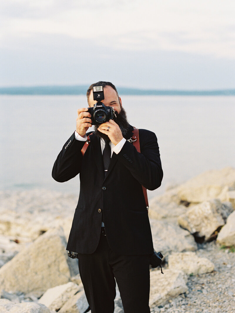 Photographer Jake Ford smiling with a film camera at Haus 820 wedding venue in Lakeland, Florida.