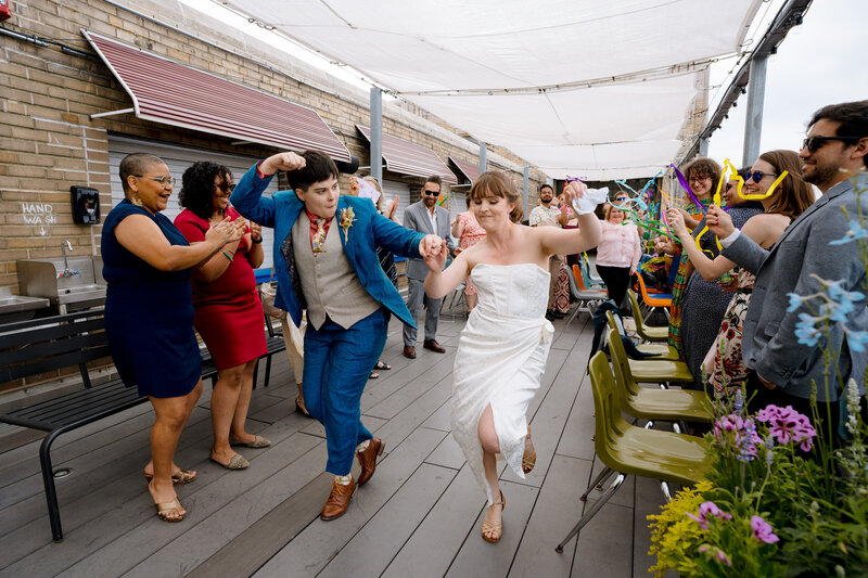 A wedding couple dancing as they walk in between their wedding guests.