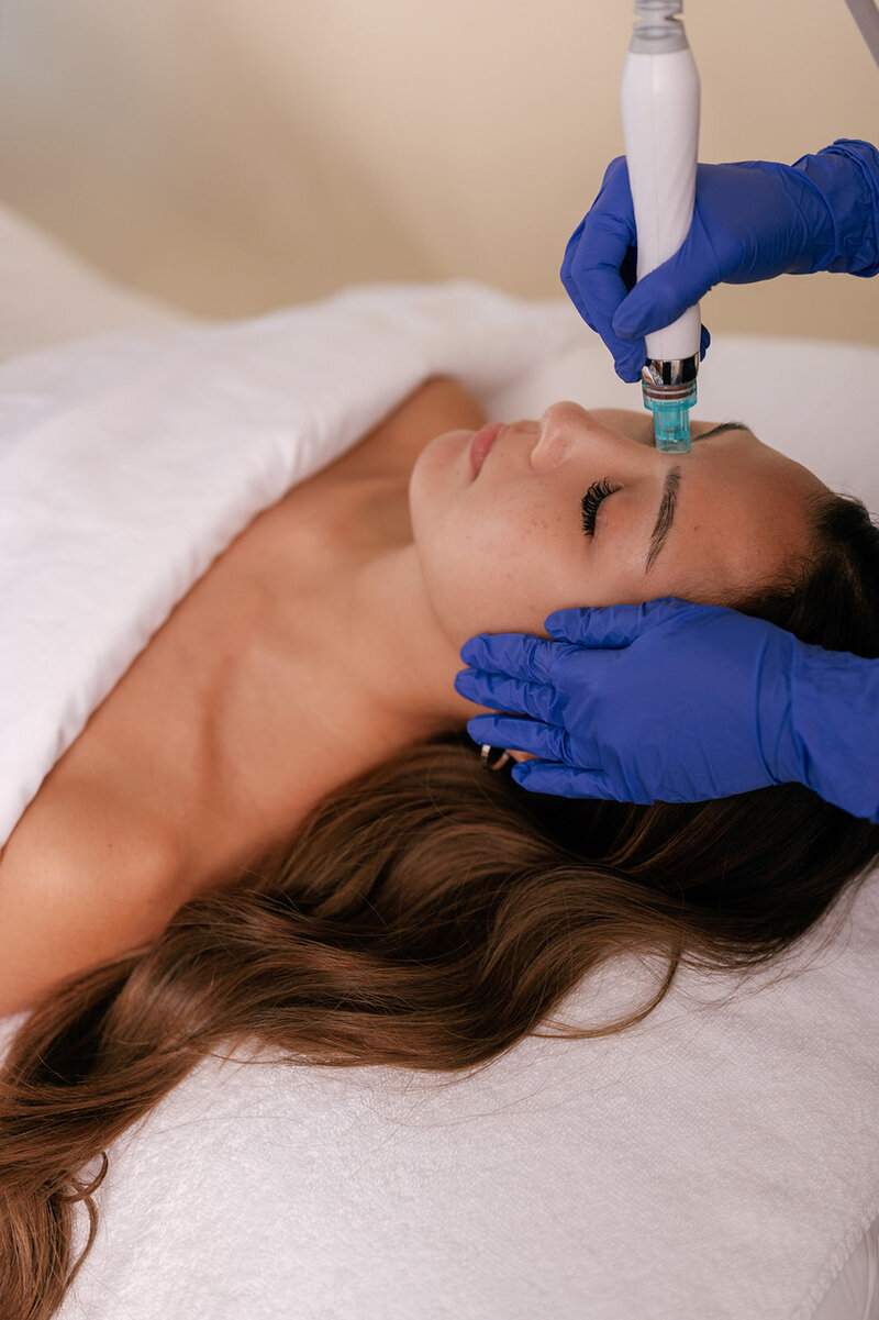 Woman laying down receiving a facial treament from medspa practitioner