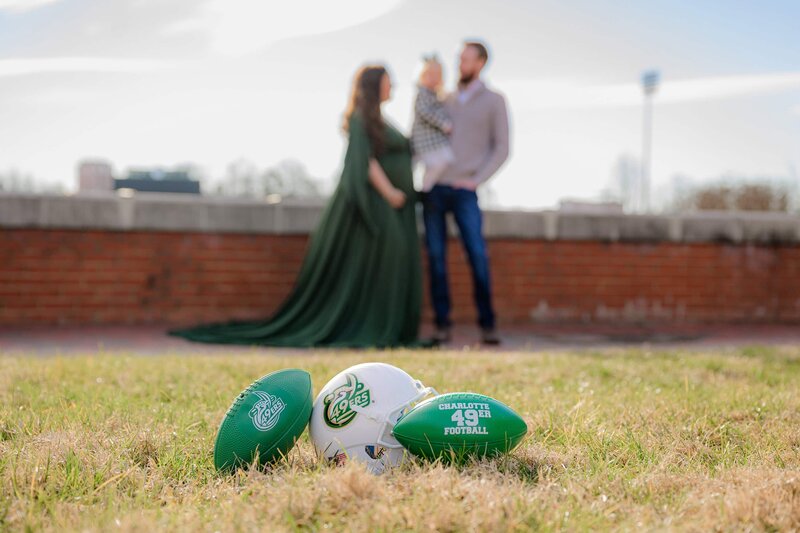 charlotte 49ers footballs in foreground of family maternity session at UNCC campus