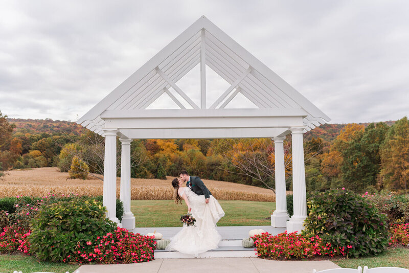 A bride and groom kissing under a small gazebo.