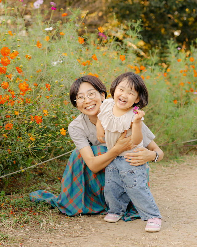 Photographer Miho is hugging her 3yo daughter in a flower field