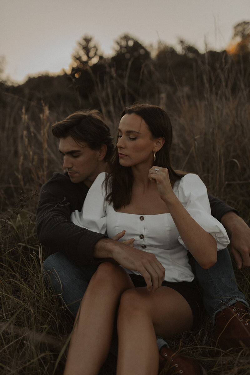 Young couple seated in the heart of a field, striking a pose for a captivating photoshoot