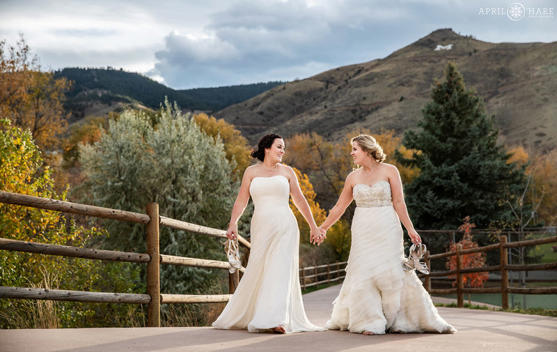 Two brides walk down the path with their shoes off at The Golden Hotel