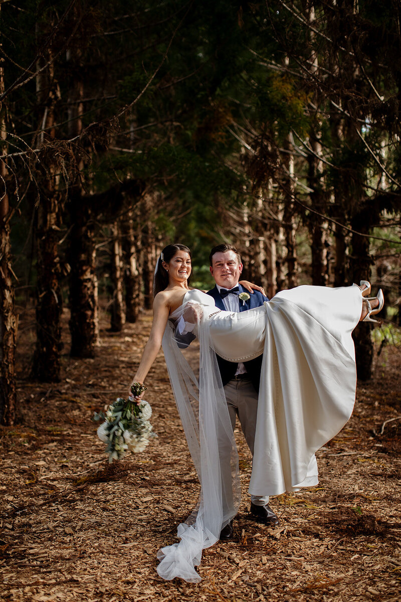 Groom carries his bride at the woods in the forest