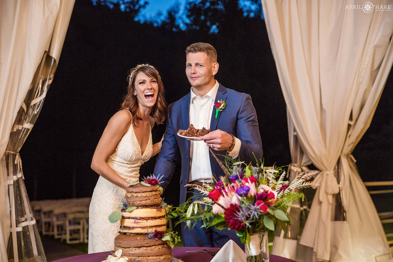 Couple laugh and cut their cake inside the open air tent wedding reception at Wedgewood Weddings Boulder Creek