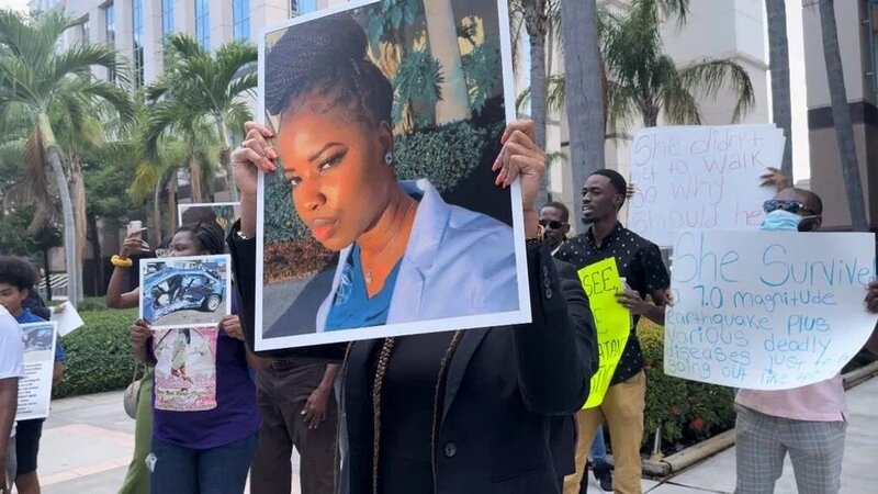 Black families standing in front of Palm Beach Court House holding signs of a black nurse who was in a collision