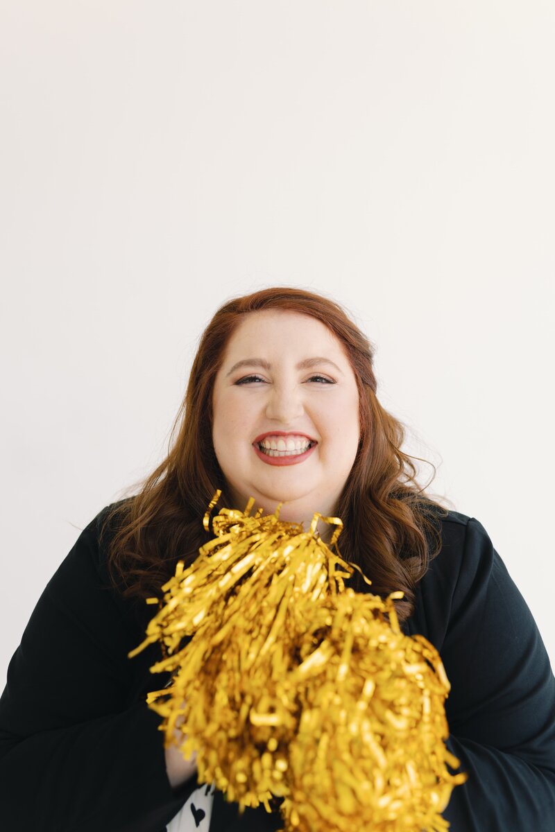 woman with huge smile holding gold pompoms