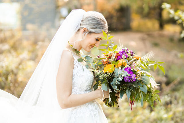 Bride smells her colorful bouquet at Historic London Town Gardens, Wedding Day