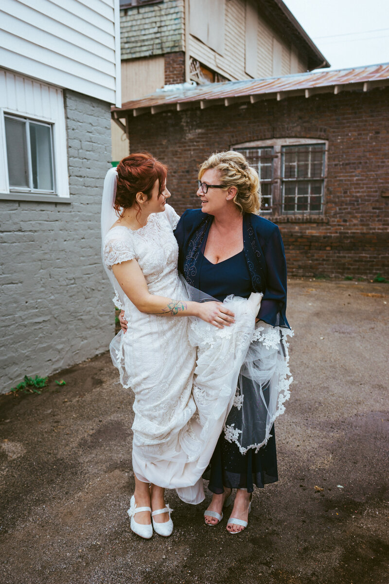 bride in white dress hugging mother