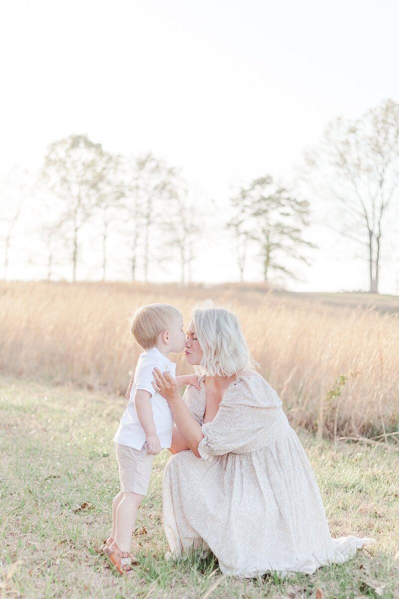 Mom kneeling down sharing kiss with 3 year old little boy during family photography session with 5U Photography in Birmingham AL