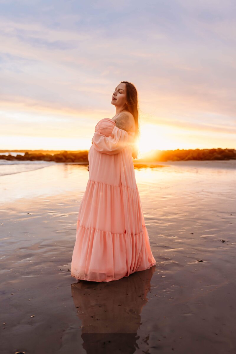 Pregnant mom posing in a floral dress at the beach