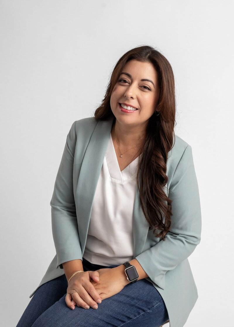 Jennis from She Blooms Studio, Showit web designer for mom entrepreneurs, sitting and smiling. 