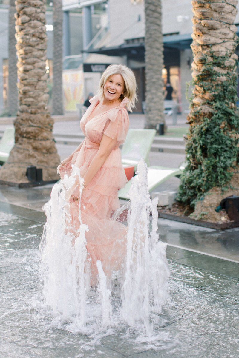 Phoenix woman and mother in taupe dress playing in a water fountain