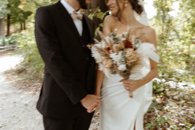 In a beautiful garden in Virginia, a couple stands side by side with a bouquet of flowers after getting married