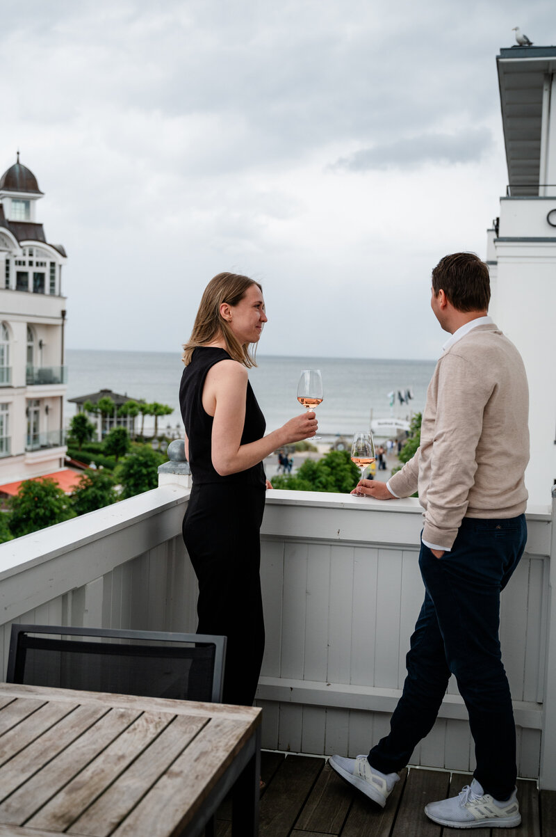 Pärchen mit einem Glas Wein auf dem Balkon eines Zimmer im LOEV Hotel.