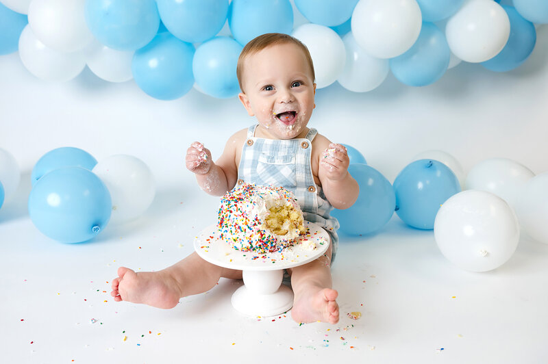 one year old boy sitting with gold balloons for a boho cake smash session