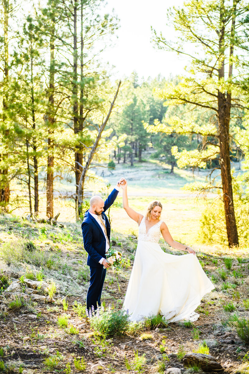 Flagstaff wedding bride and groom couple twirl wedding dress in pine trees golden hour sunlight