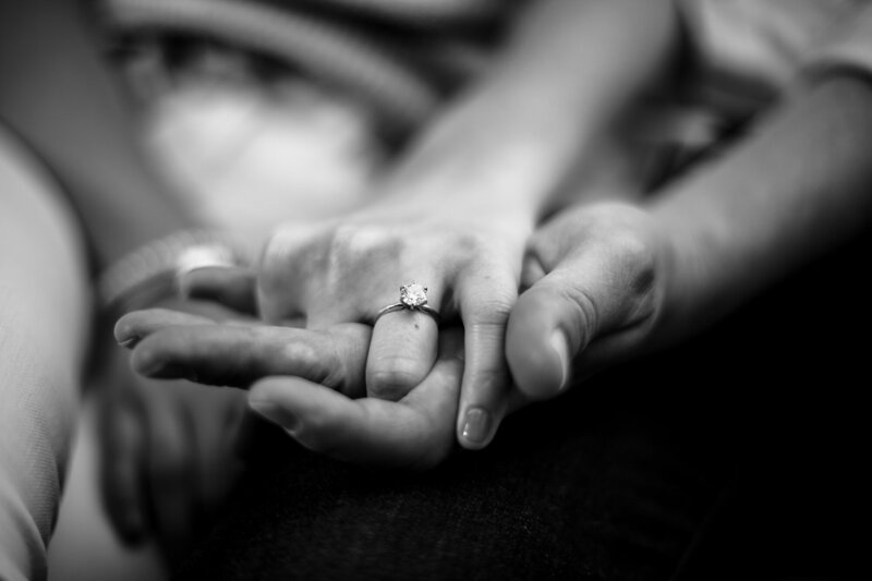 Clasped hands of couple with focus on woman's engagement ring