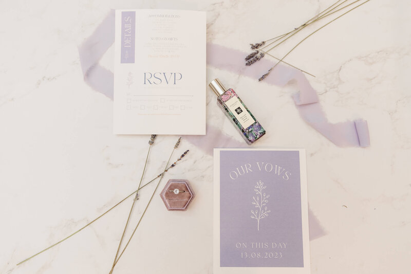 flat lay of purfume, rsvp papers with lavender stocks. 