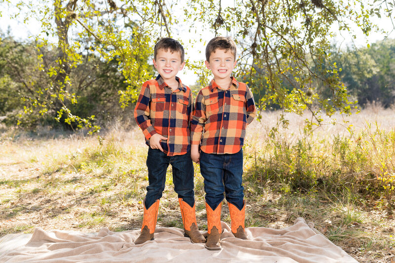 Hello & Co. Photography, twin brothers wear orange plaid and cowboy boots standing under a tree with beautiful sunlight.