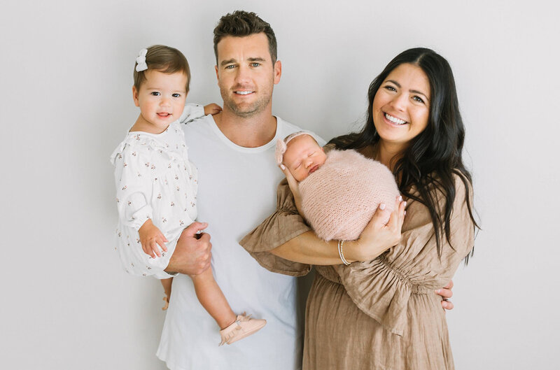 A new family of four smiles at the camera during their newborn session