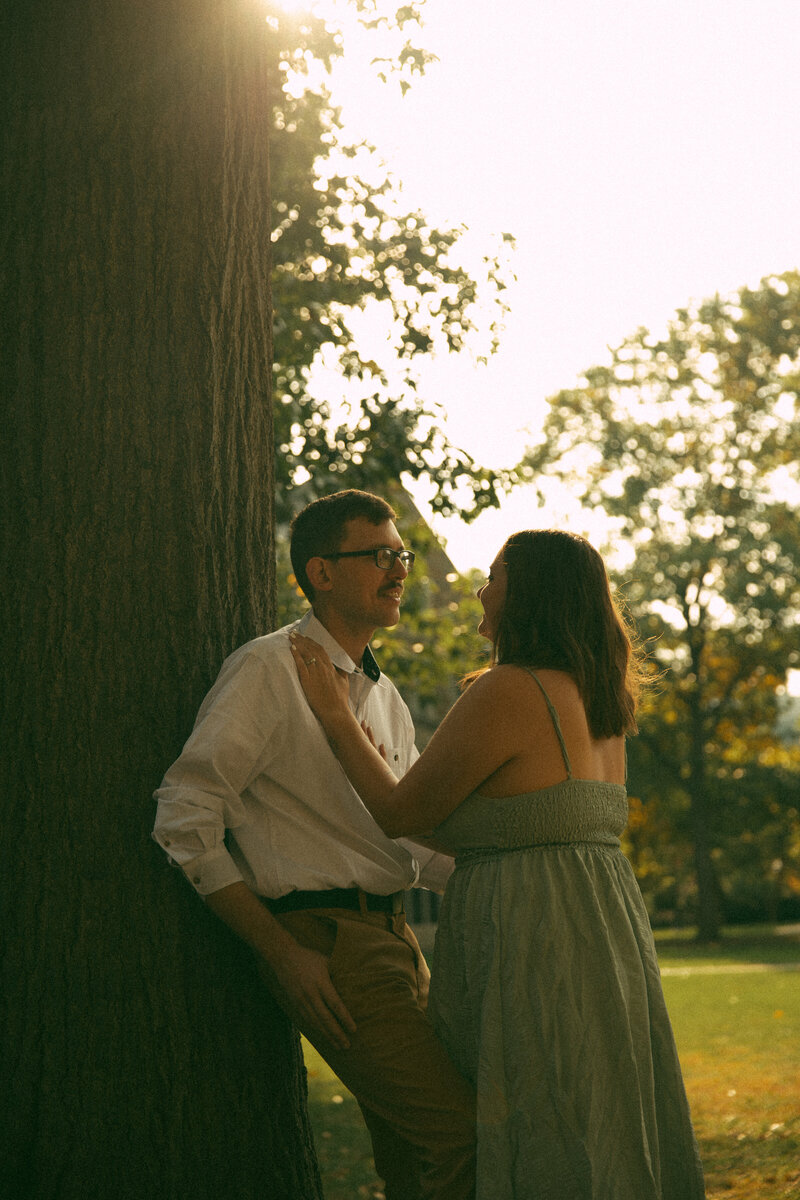 A couple sits on the edge of a wall laughing and enjoying eachother's company